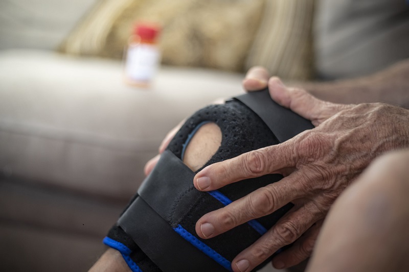 Hand holding knee in brace