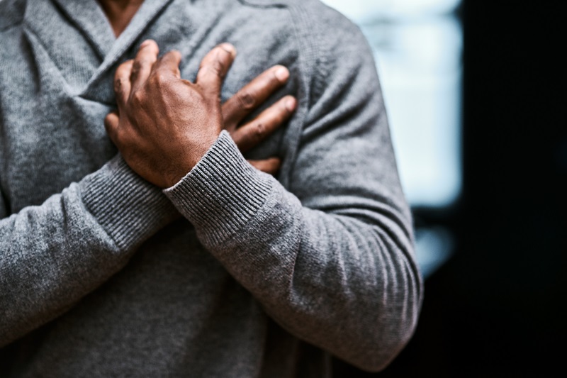 man clenches heart in pain, possibly heart attack or cardiac arrest